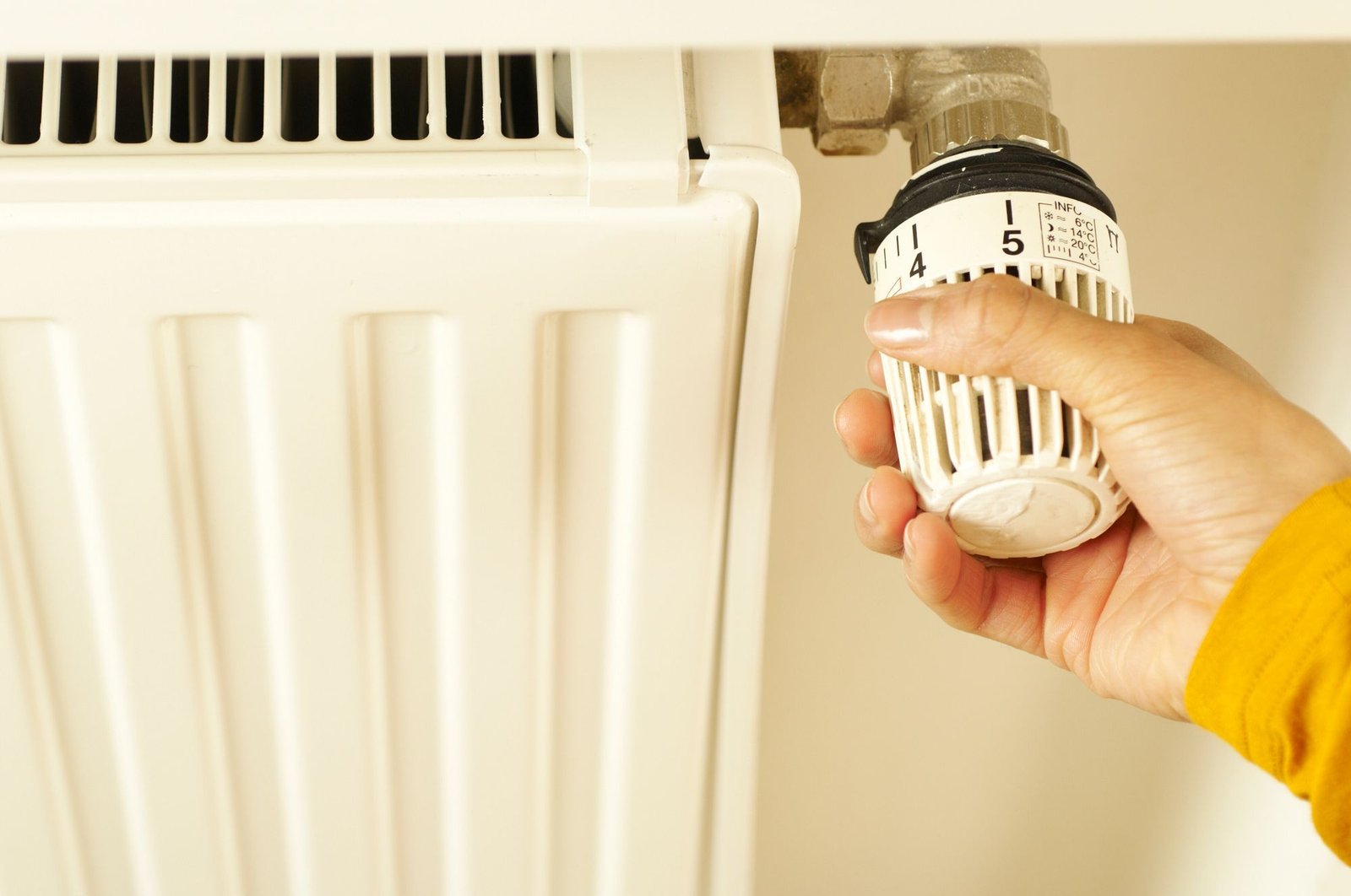 Main réglant le robinet thermostatique d’un radiateur