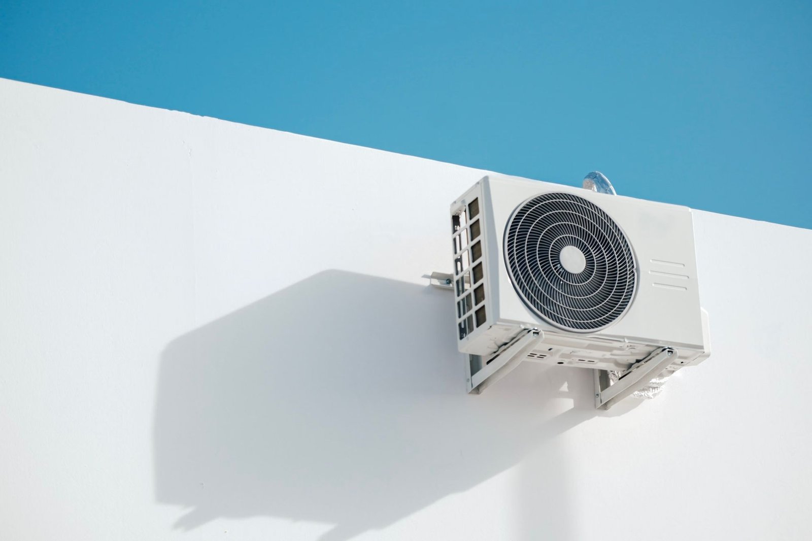 Groupe extérieur blanc fixé sur un mur, sous un ciel bleu